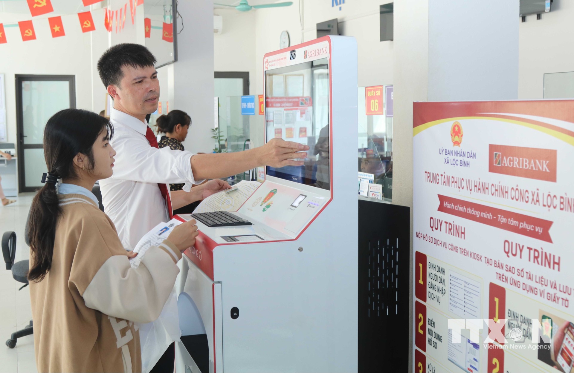 Cán bộ Agribank tỉnh Lạng Sơn hướng dẫn người dân thực hiện thủ tục hành chính qua “Trạm dịch vụ công số” xã Lộc Bình. (Ảnh: Quang Duy/TTXVN)